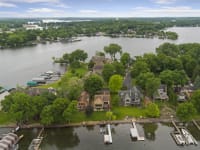 Aerial view of houses by a calm lake surrounded by greenery.