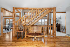Interior view of a home showcasing a rustic wooden bench, staircase, and dining area with natural light filtering in.
