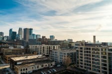 A city skyline featuring a mix of modern and older buildings under a partly cloudy sky.