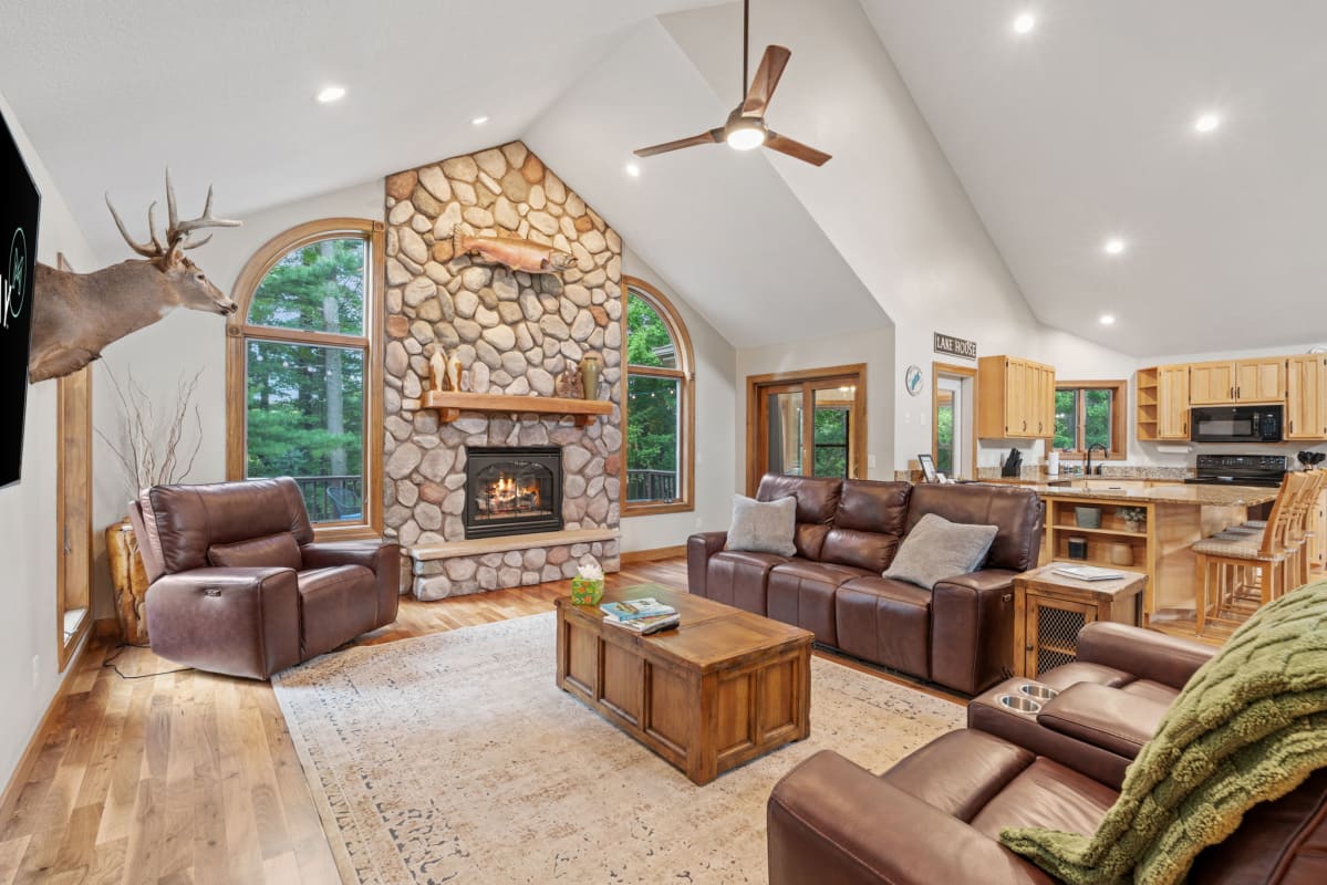 Relax in your spacious living room with stone fireplace, leather seating, and vaulted ceilings creating the perfect mountain retreat atmosphere.