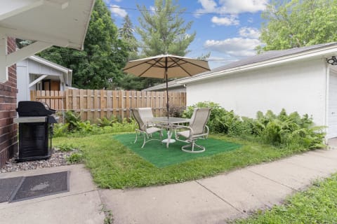 Outdoor patio with a grill and dining table under an umbrella.