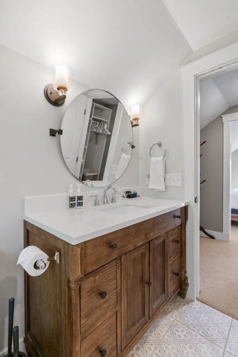 Stylish bathroom interior featuring a wooden vanity with a white countertop and circular mirror.