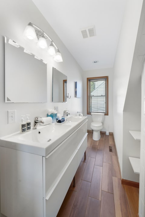 Modern bathroom with double sink and natural lighting.