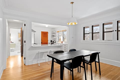 Modern dining area with a wooden table and black chairs, leading to a stylish kitchen.