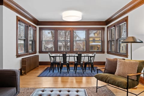 A cozy living room featuring large windows, a dining table, and comfortable seating.