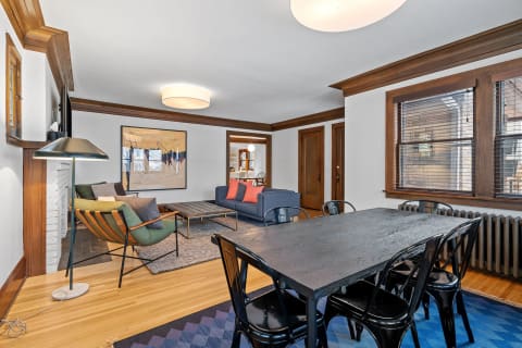 Stylish living room with blue sofa, black dining table, and wooden accents.