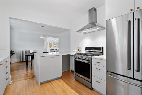 Contemporary kitchen featuring stainless steel range and white cabinetry.
