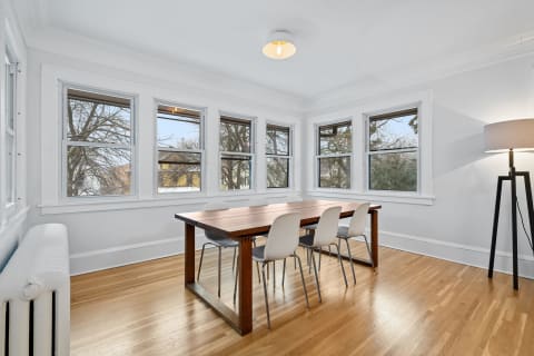 Bright dining room featuring a wooden table and white chairs by large windows.