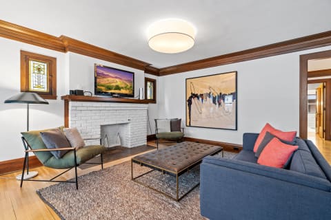 Modern living room with blue sofa, green armchair, and abstract painting.