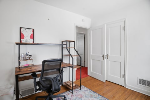 A modern workspace featuring a wooden desk, ergonomic chair, and abstract art on the wall.