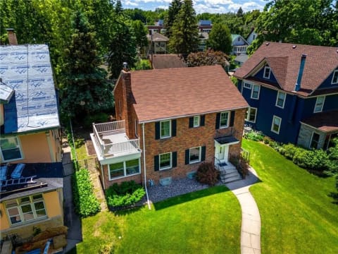 Aerial view of a brick home in a residential neighborhood with well-maintained landscaping.
