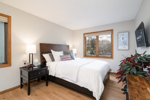 Cozy bedroom with a bed, bedside table, modern lamp, and window view.