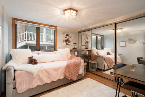 Cozy living room with a pink quilted sofa, teddy bear, and wooden elements.