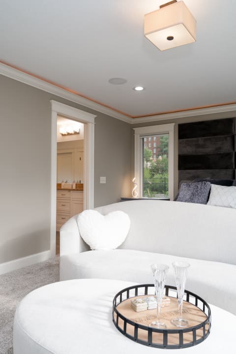 A beautifully designed living room with a white sofa, heart-shaped pillow, and elegant decor.