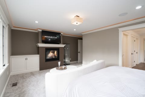 Stylish bedroom with a fireplace, white bed, and modern furnishings.