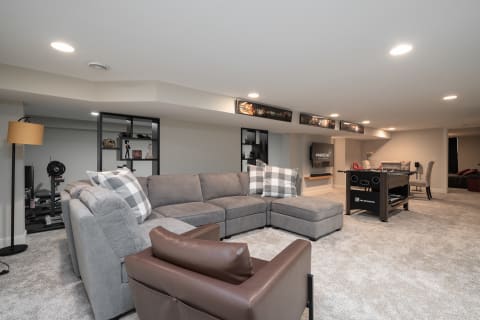 Cozy basement living space featuring a sectional sofa, foosball table, and elegant decor.
