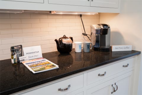 Kitchen countertop with coffee maker, mugs, teapot, and a welcome note.
