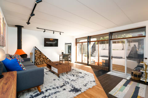 Modern living room with gray sofa, colorful pillows, orange fireplace, and sliding glass doors leading outdoors.