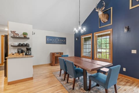 A dining room featuring a wooden table, blue chairs, and a rustic wall decor.