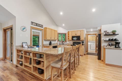 Spacious kitchen with granite countertop, wooden cabinets, and modern appliances in a lake house setting.