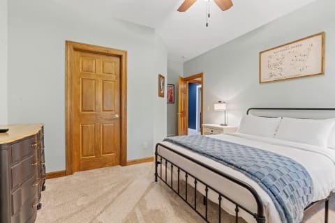 Cozy bedroom with a metal bed frame, blue throw blanket, and wooden accents.