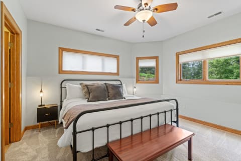 A modern bedroom featuring a black metal bed, plush bedding, and wooden accents.