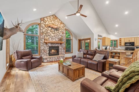 A cozy living room featuring a stone fireplace, leather sofas, and wood accents.