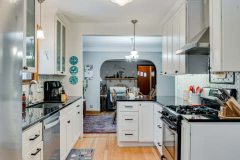 Modern kitchen with white cabinets and black countertops, looking into a dining area.