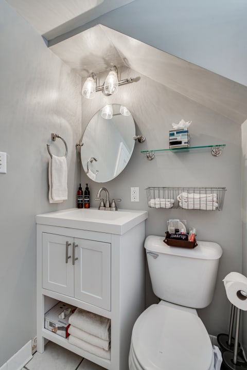 Compact bathroom featuring a white vanity, round mirror, and modern accessories.