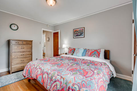 Interior of a cozy bedroom featuring a double bed with a colorful bedspread and wooden furniture.