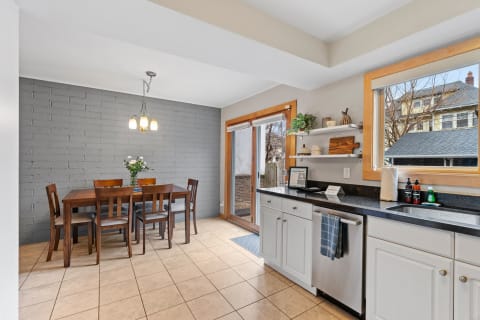 A modern kitchen-dining area with a wooden table, grey walls, and a sleek kitchen counter.