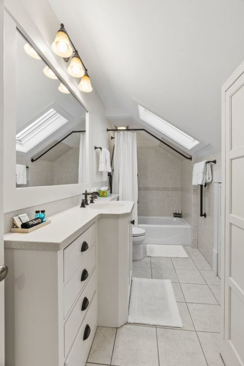 Bright attic bathroom with skylights, elegant vanity, and cozy bathtub.