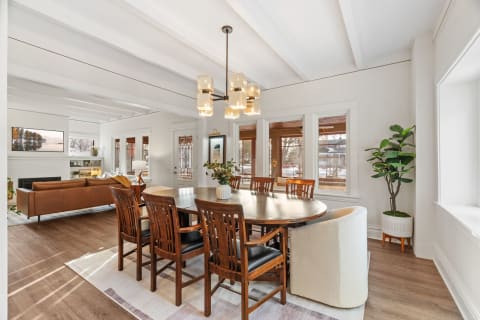 Elegant dining area with a round table, wooden chairs, and a cozy living room.