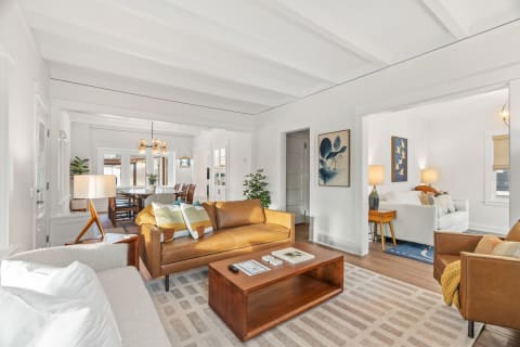 A modern living area with leather seating, wooden coffee table, and bright decor.