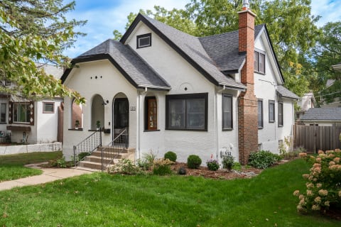 A single-story white house with a pitched black roof and green lawn.