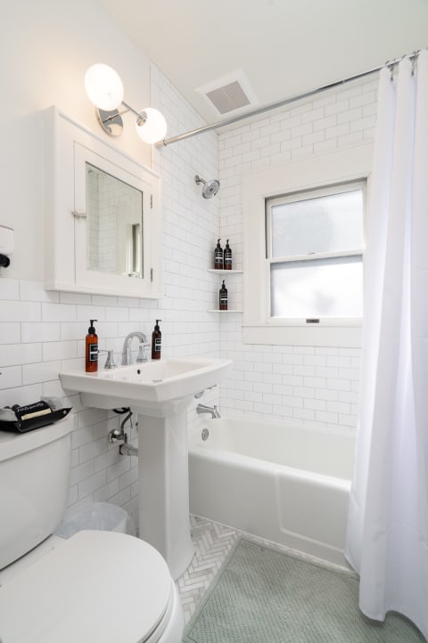 A bright and clean bathroom with white subway tiles, a bathtub, and modern fixtures.