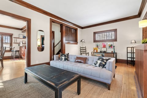 A living room featuring a gray sofa, black coffee table, and wooden decor elements.