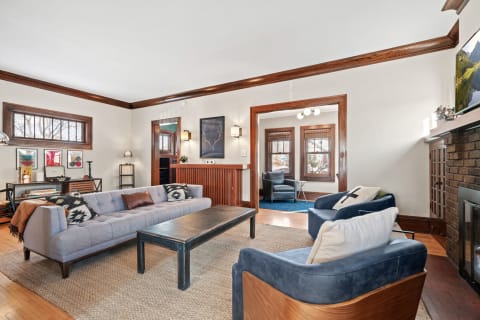 A modern living room featuring a light blue couch, dark blue chairs, and a cozy fireplace.