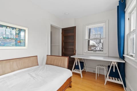 Minimalist bedroom with double bed, desk, and window.