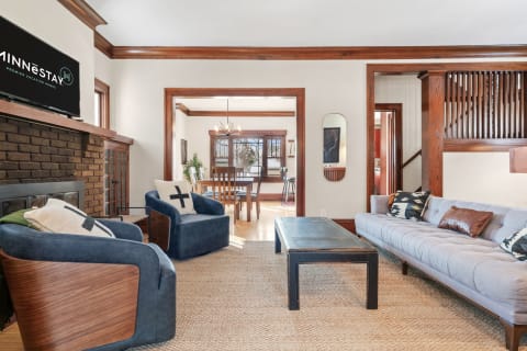 Living room with blue chairs, gray sectional, black coffee table, and a dining area in the background.