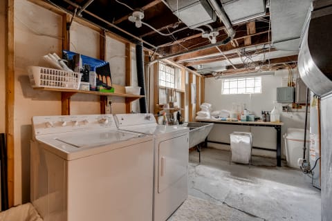 Laundry room with washing machine, dryer, and organized work space in a basement.