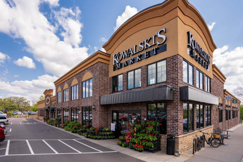 Kowalski's Market exterior with colorful flowers and a clear sky.