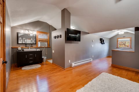 A stylish bathroom with dark wood vanity, mirror, and TV.