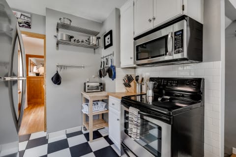 A contemporary kitchen with stainless steel appliances, open shelving, and a checkered floor.