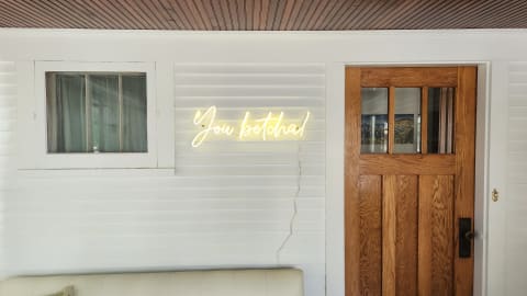 Cozy entryway with a neon sign saying 'You betcha!' and a wooden door.