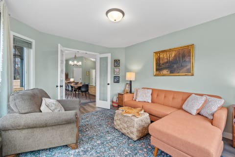 Warm living room featuring an orange sectional couch and a gray chair, with a view into the dining area.