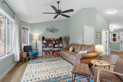 Cozy living room featuring a brown sectional couch, blue armchair, and wooden bookshelf with decorative items.