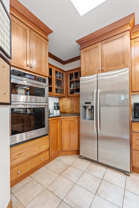 Interior view of a kitchen corner featuring oak cabinetry and a stainless steel refrigerator.
