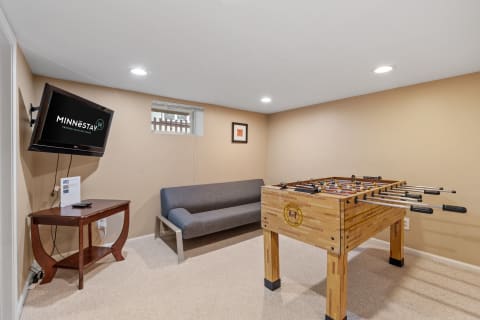 Cozy entertainment room with foosball table, sofa, and a mounted television.