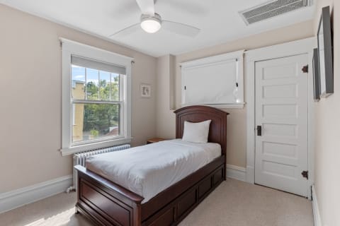 Cozy bedroom with single wooden bed, window, and white door.
